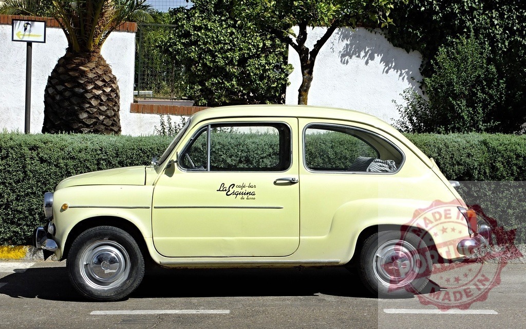 Classic Seat 600 parked near a palm tree in Spain | Vintage Seat 600 advertising a cafe, parked on a street near a palm tree and a hedge in Spain - Realized with Pictrs.com