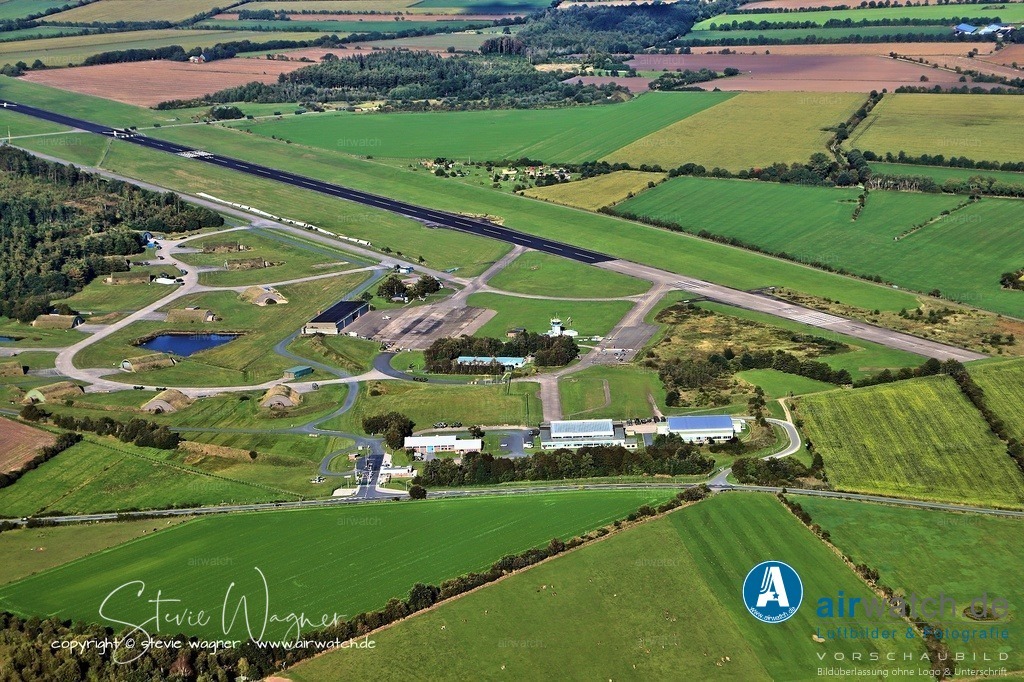 Luftbild Flughafen Husum-Schwesing - Der Flugplatz Husum-Schwesing (IATA-Code: QHU, ICAO-Code: EDXJ) ist ein Verkehrslandeplatz in der Nähe von Husum | Der Flugplatz Husum-Schwesing (IATA-Code: QHU, ICAO-Code: EDXJ) ist ein Verkehrslandeplatz in der Nähe von Husum und entstand aus einem Teil des ehemaligen, inzwischen inaktiven Fliegerhorsts Husum JABOG 41, wobei ein anderer Teil weiterhin von der Luftwaffe als Standort einer Flugabwehrraketengruppe genutzt wird. - Luftbild Position: Queranflug Piste 03 -