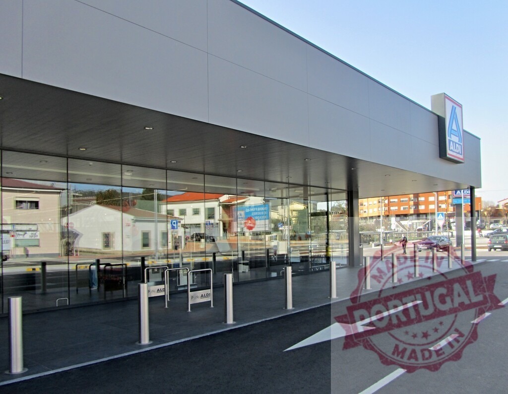 Aldi supermarket exterior with modern architecture and parking lot | Aldi grocery store building facade with reflective windows and entrance area during the day - Realized with Pictrs.com