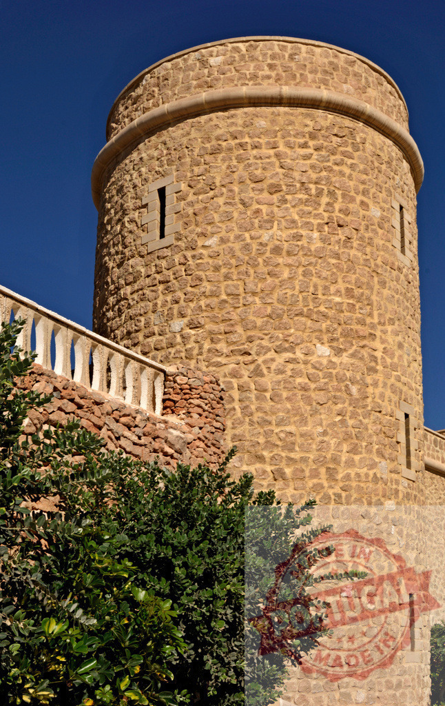 Stone fortress tower reaching blue sky | Round stone tower with narrow windows and balcony railing against a clear blue sky - Realisiert mit Pictrs.com