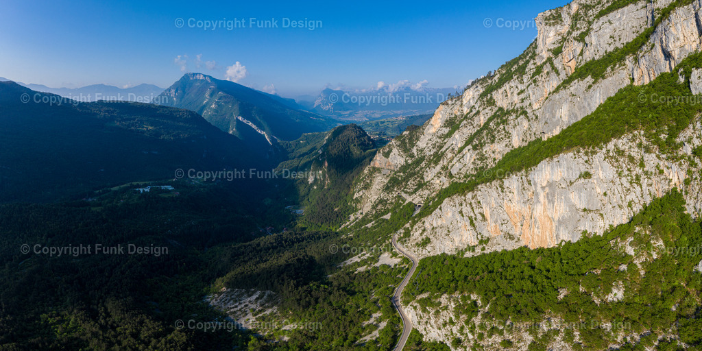 Bergstraße entlang der Felswand – Italien | Eine schmale Bergstraße zieht sich wie eine Linie entlang einer gewaltigen Felswand und öffnet den Blick weit ins Tal. Die Szene wirkt ruhig und mächtig zugleich und verbindet Naturdrama mit dem Gefühl von Freiheit und Unterwegssein.