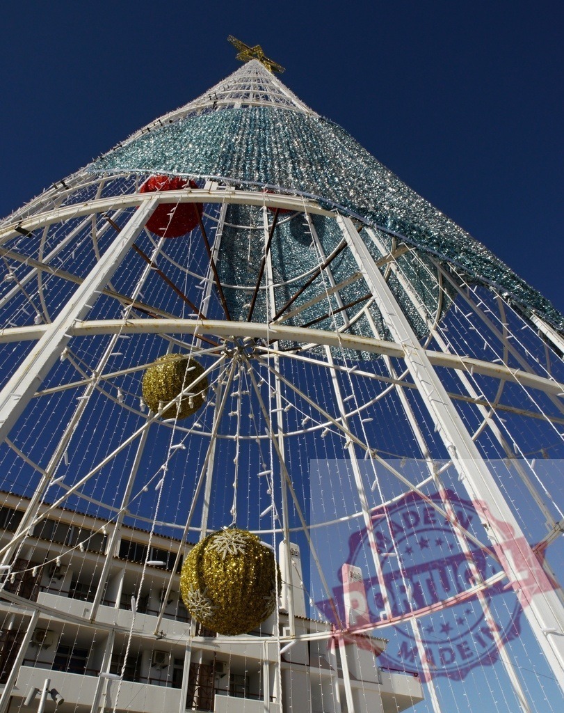 Giant christmas tree standing tall against blue sky | Giant christmas tree with golden ornaments and lights standing tall against a clear blue sky - Realisiert mit Pictrs.com