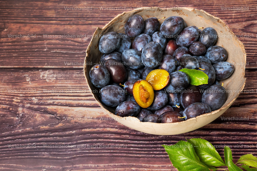 Eine rustikale Schale voll mit erntefrischen Pflaumen | Eine rustikale Schale voll mit erntefrischen Pflaumen. Eine aufgeschnitten. - Realisiert mit Pictrs.com