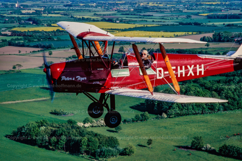 PLBDD_air2air_TigerMoth_01_90x60 | Luftbild. Doppeldecker vom Typ TIGER MOTH über landwirtschaftlichen Flächen mit Feldern und Wäldern der Landschaft Angeln in Schleswig-Holstein. ___ Das Foto ist eine Reproduktion von einem Farbdia. - Realisiert mit Pictrs.com