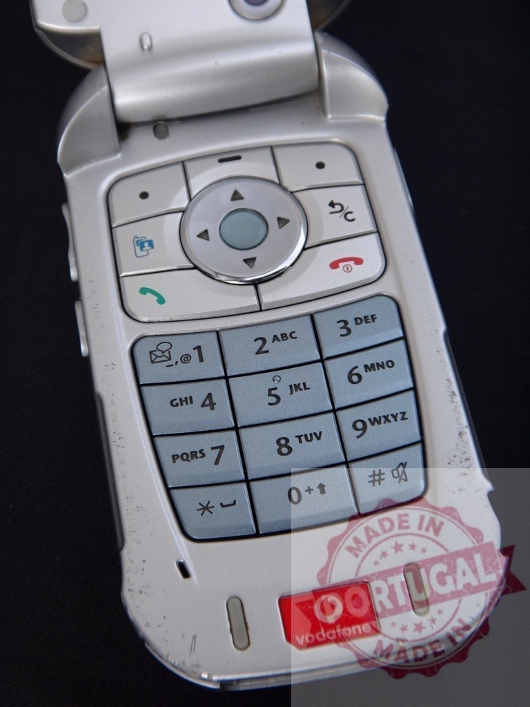 Old Vodafone flip phone showing keypad and navigation buttons | Old used and scratched flip phone with Vodafone logo, keypad and navigation buttons - Realized with Pictrs.com