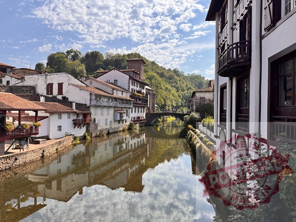 Saint-Jean-Pied-de-Port Nive river reflection with Basque architecture | Historic Basque houses reflecting in the Nive river under a bright blue sky - Realized with Pictrs.com