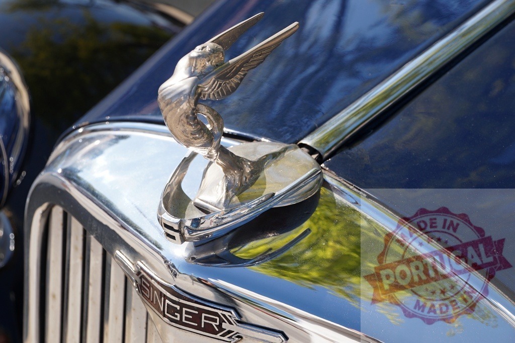 Vintage Singer car hood ornament depicting a winged goddess | Vintage Singer car hood ornament showcasing a classic winged goddess design on a blue hood - Realized with Pictrs.com