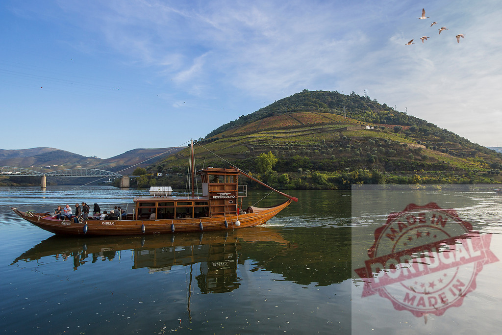 Rabelo boat cruising Douro River vineyards, Portugal. Portugal - Norte | Rabelo boat carrying tourists on the Douro River with terraced vineyards and mountains - Realized with Pictrs.com