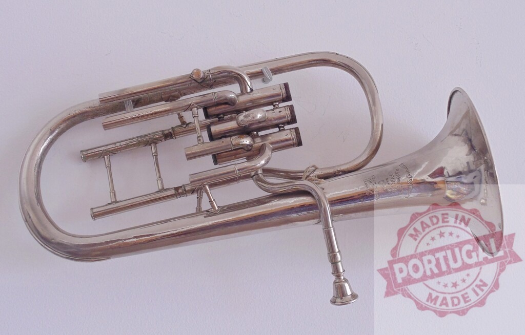 Vintage silver plated oval tenor horn lying on white background | High angle view of a beautiful vintage Couesnon &amp; Cie Monopole Conservatoire oval tenor horn lying on a white background - Realized with Pictrs.com