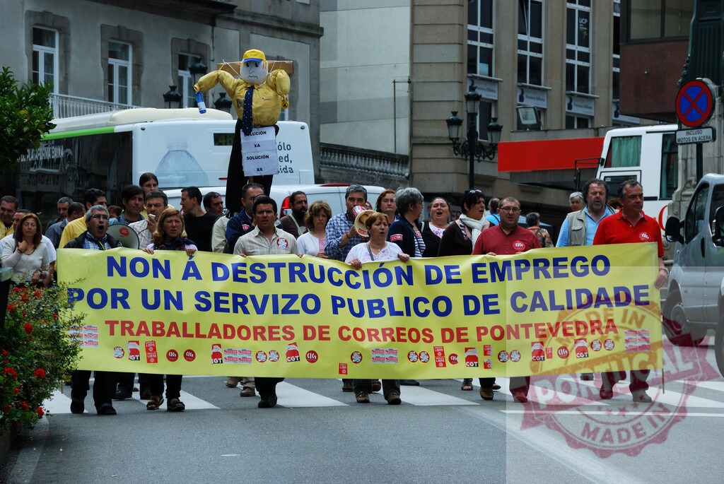 Correos workers protesting against job destruction in Pontevedra, Spain | Protesters holding a banner during a street march advocating for public service quality - Realized with Pictrs.com