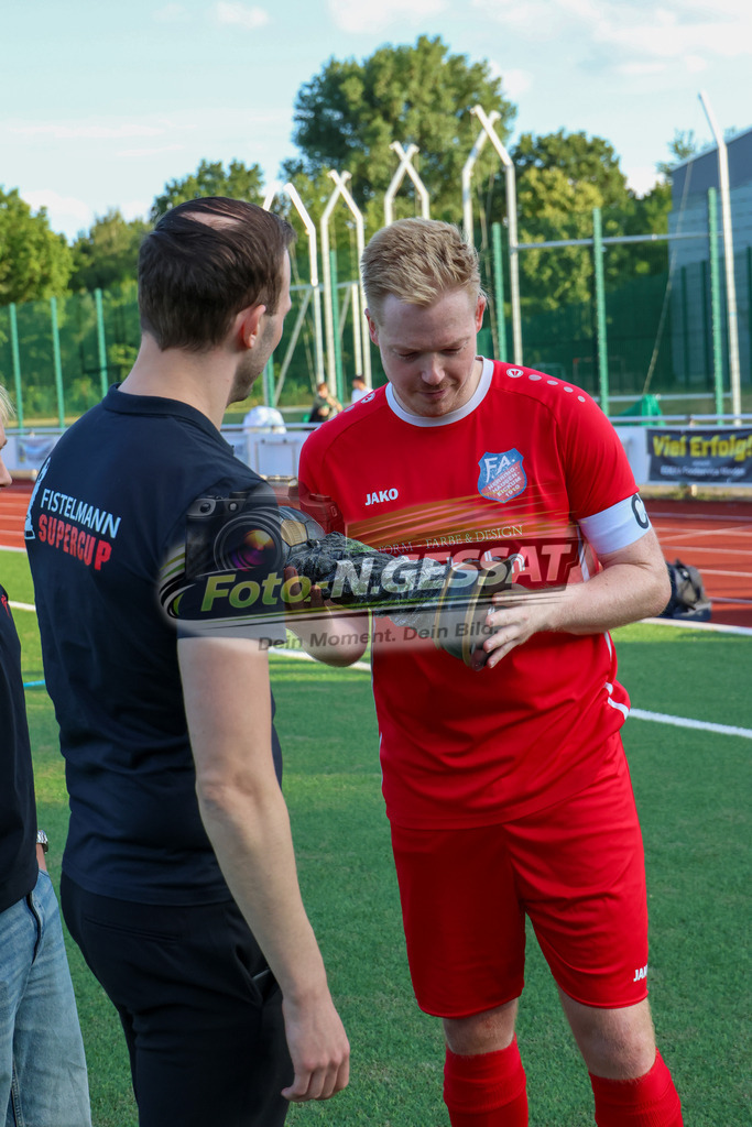 TuS Bardüttingdorf - TuRa Löhne | Auf dem Bild zu sehen: Pokalübergabe an rot SG FA Herringhausen/Eickum: Tim Spiker durch Fabian Haarmann SV Löhne-Obernbeck, SG FA Herringhausen/Eickum, Saison 26/27, Fistelmann SuperCup - Realisiert mit Pictrs.com