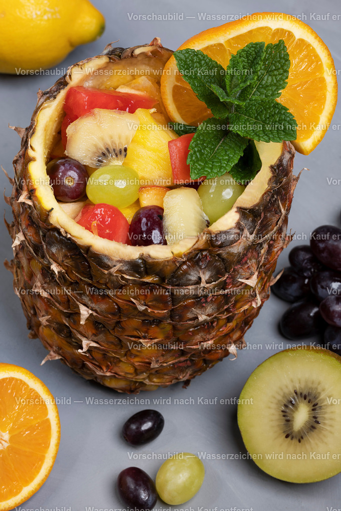 frischer Obstsalat in ausgehöhlter Ananas serviert | frischer Obstsalat in ausgehöhlter Ananas serviert, dekoriert mit Obst und Minze - Realisiert mit Pictrs.com