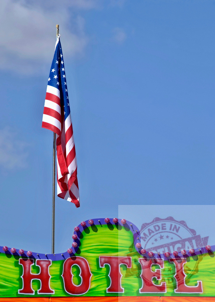 American flag flying above retro hotel sign | American flag waving above a colorful, vintage hotel sign on a bright day - Realisiert mit Pictrs.com