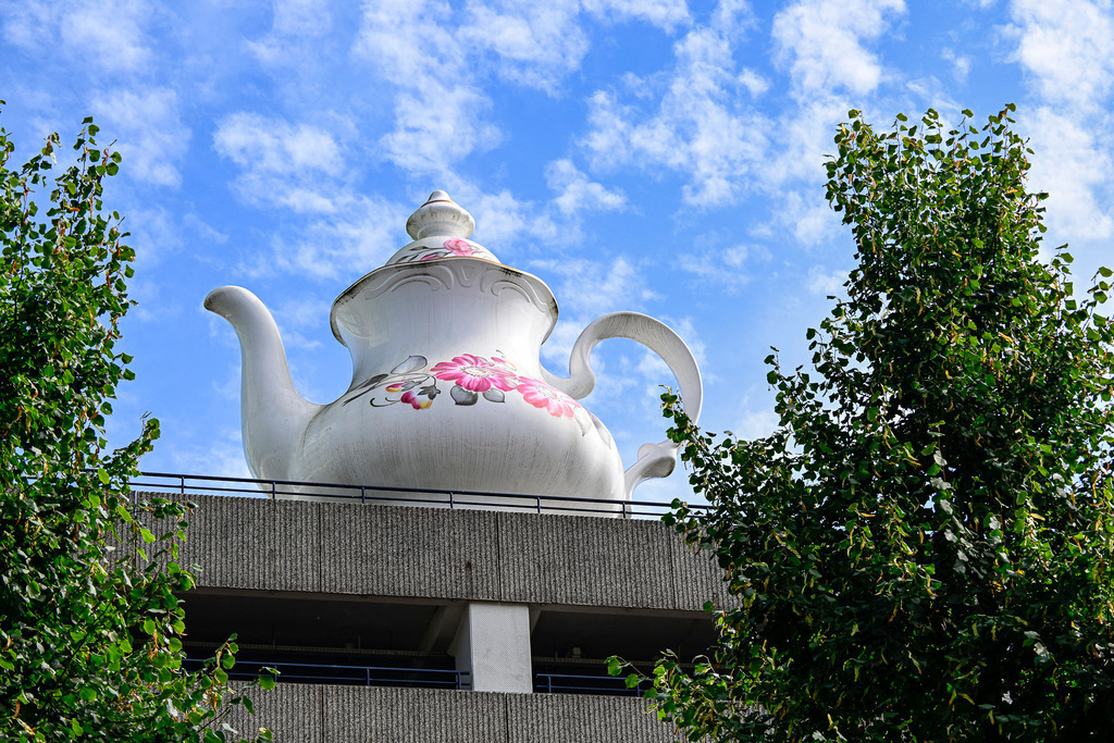 Himmlische Teekanne in Utrecht | Diese markante Skulptur hat eine sehr charmante Entstehungsgeschichte, die eng mit der Stadtentwicklung von Utrecht verknüpft ist:Name und HerkunftDie Skulptur trägt den offiziellen Titel "Celestial Teapot" (Himmlische Teekanne). Sie wurde von der niederländischen Künstlerin Lily van der Stokker entworfen und im Jahr 2013 installiert.Der Kontext: "Call of the Mall"Die Kanne wurde ursprünglich für die Kunstausstellung Call of the Mall geschaffen. Zu dieser Zeit befand sich das gesamte Bahnhofsviertel und das Einkaufszentrum Hoog Catharijne in einer massiven Umbauphase. Zwischen Baustellen, Lärm und nacktem Beton sollte die Kanne einen bewussten Gegenpunkt setzen.Technische Daten:Größe: Die Kanne ist etwa 7 Meter hoch.Gewicht: Sie wiegt stolze 3,5 Tonnen.Material: Sie ist aus Kunststoff gefertigt, sieht aber durch die glänzende Lackierung täuschend echt nach klassischem Porzellan aus. - Realisiert mit Pictrs.com