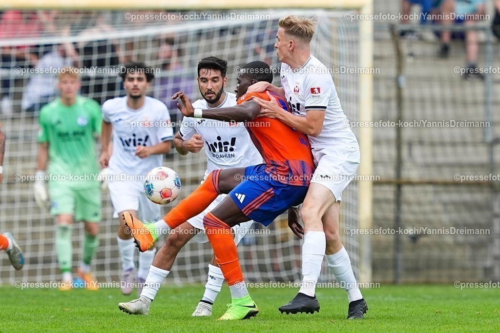 xYDR20072501114 | 20.07.2025, xydrx, Fußball, Rot Weiss Ahlen - FC Schalke 04, Testspiel, Wersestadion: Bryan Lasme (FC Schalke 04 #11) im Zweikampf gegen Ben Binyamin (Rot Weiss Ahlen #20) und Erik Heidbrink (Rot Weiss Ahlen #18)