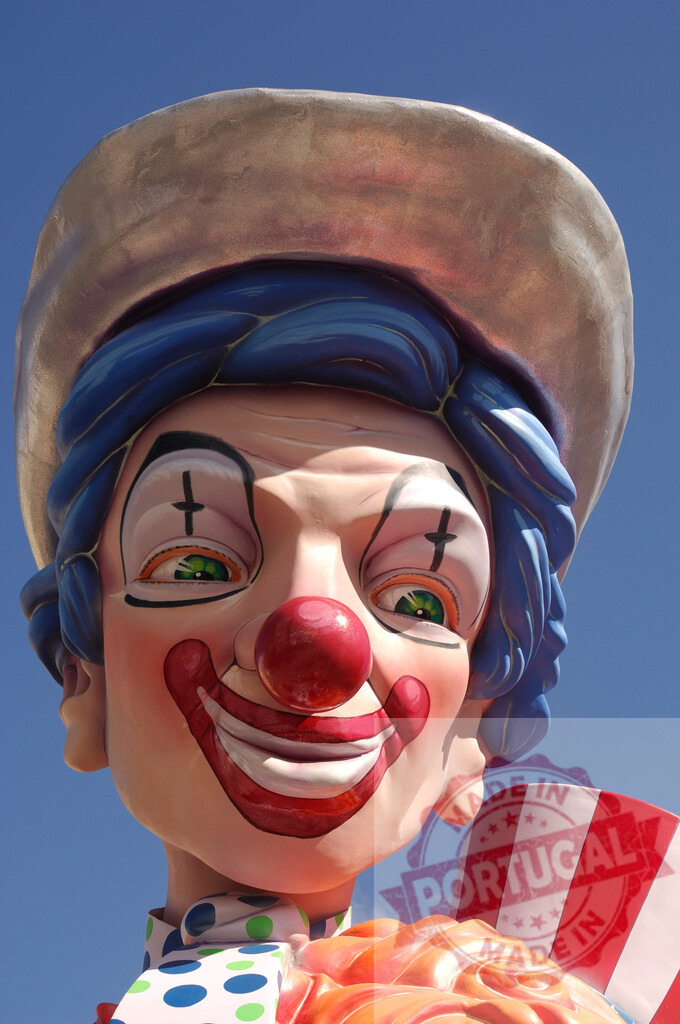Clown character statue smiling at carnival parade | Clown float head with painted smile and blue hair on sunny day - Realized with Pictrs.com