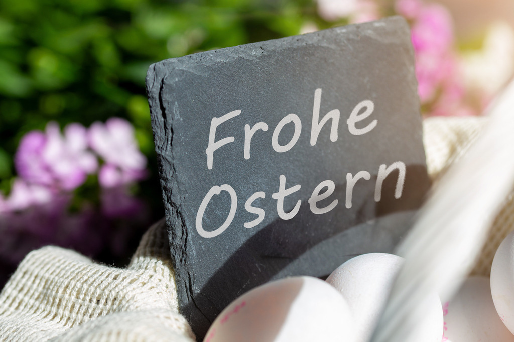Frohe Ostern - Ostergrüße mit Schild, Eiern und Blumen | Schild mit (digital hinzugefügtem) Text FROHE OSTERN in einem Korb mit frischen Eiern, im Hintergrund Frühlingsblumen - Realisiert mit Pictrs.com