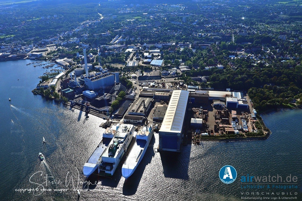 Luftbild Flensburger Schiffbau Gesellschaft FSG - verfügt über eine Schiffbauhalle, die 1982 errichtet wurde und eine Länge von 275 Metern hat. | Die Flensburger Schiffbau-Gesellschaft (FSG) verfügt über eine Schiffbauhalle, die 1982 errichtet wurde und eine Länge von 275 Metern hat. Diese Halle ersetzte zwei der drei vorhandenen Hellinge und beherbergt seitdem eine eigene Helling, von der aus alle Stapelläufe bei der FSG stattfinden. Die Halle ist Teil einer umfassenden Grundsanierung der Werft, die auch die Errichtung eines neuen Gebäudes mit Verwaltungs- und Konstruktionsbüros umfasste. Die Schiffbauhalle befindet sich am Standort der Werft in Flensburg, direkt am Flensburger Hafen.