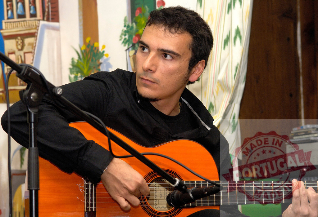 Musician playing acoustic guitar during live performance | Musician concentrating while playing an acoustic guitar into a microphone during a performance - Realized with Pictrs.com
