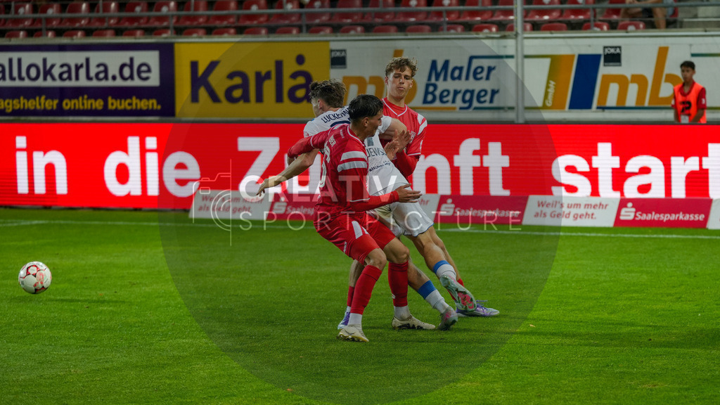 Fußball, Herren, Saison 2025/2026, Regionalliga Nordost, 5. Spieltag, Hallescher FC vs. FSV 63 Luckenwalde, Dienstag 26.08.2025, Leuna-Chemie-Stadion Halle, | Fußball, Herren, Saison 2025/2026, Regionalliga Nordost, 5. Spieltag, Hallescher FC vs. FSV 63 Luckenwalde, Dienstag 26.08.2025, Leuna-Chemie-Stadion Halle, Im Bild: Pierre Weber und Felix Langhammer (rot, Halle) bringen Tim Maciejewski (weiß, Luckenwalde) zu Fall. - Realisiert mit Pictrs.com