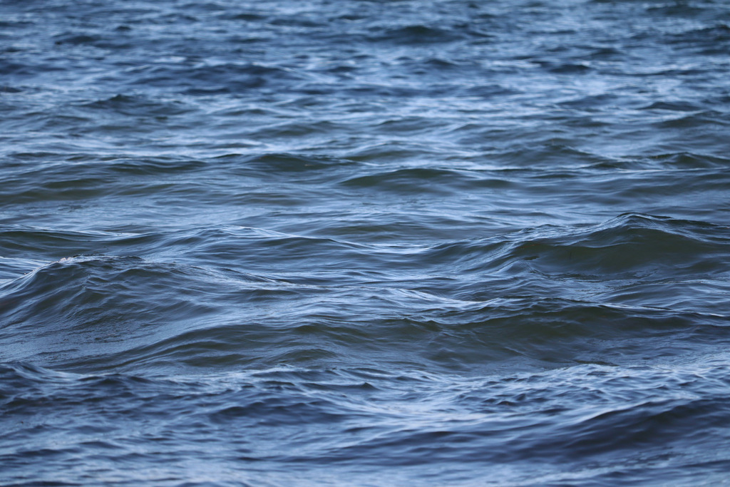 Wandbild: Wellen auf dem Meer in Damp | Ein faszinierendes Lichtspiel auf Licht glitzern und eine sanfte Reflexion auf der Wasseroberfläche erzeugen. Die verschiedenen Blautöne verleihen der Szene Tiefe und Lebendigkeit, während das Sonnenlicht die Dynamik des Wassers wunderschön hervorhebt. Ein perfektes Motiv für Ihr Zuhause, das Ruhe und maritime Eleganz vermittelt.  - Realisiert mit Pictrs.com