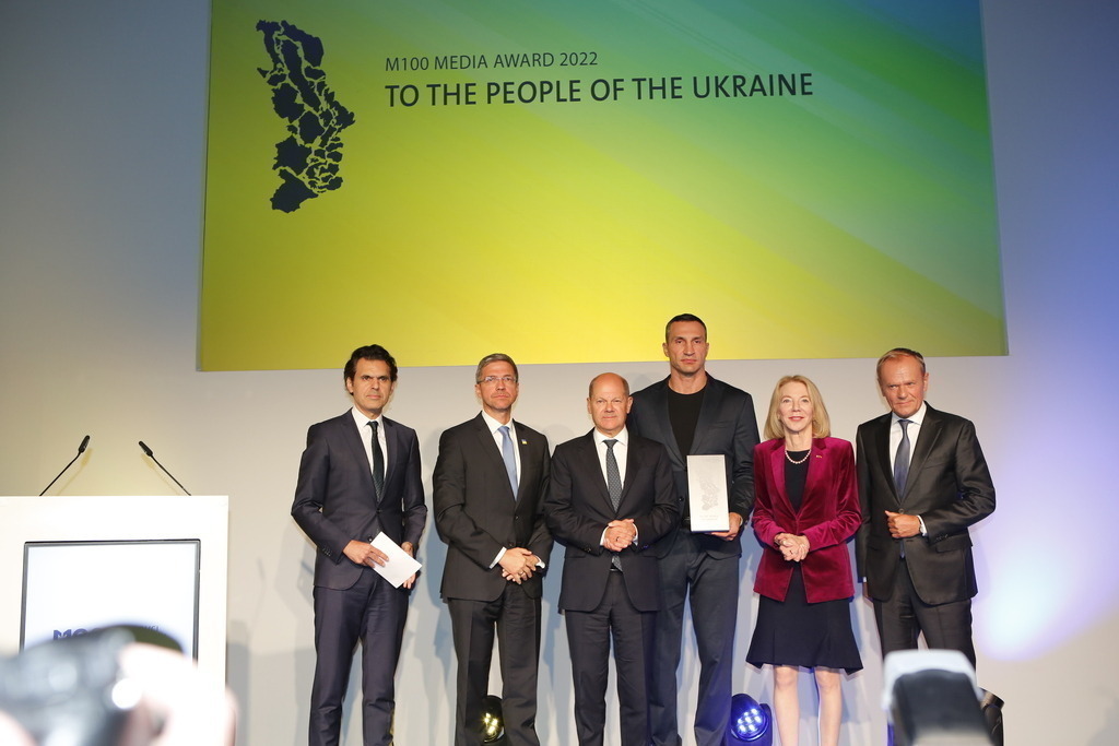 M100 Media Award: „Preis der europäischen Presse“ in Potsdam für das Ukrainische Volk verliehen. | Mit dem M100 Media Award, der sich als „Preis der europäischen Presse“ versteht, wird in diesem Jahr das Ukrainische Volk ausgezeichnet. Die Auszeichnung nimmt stellvertretend Wladimir Klitschko in der Orangerie im Park Sanssouci entgegen. Das Bild zeigt Mike Schubert, Olaf Scholz,Wladimir Klitschko, US-Botschafterin Amy Gutmann und Donald Tusk.