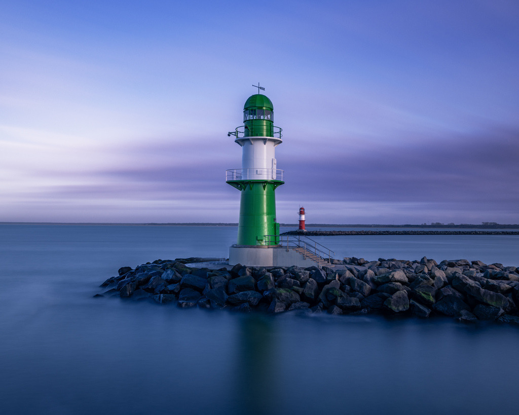 Grünes Molenfeuer an der Ostsee | Das grüne Molenfeuer steht in der blauen Stunde auf den Steinen der Mole und ragt ruhig in die Ostsee hinaus. Die Langzeitbelichtung verleiht dem Wasser eine besonders sanfte und klare Wirkung. - Realisiert mit Pictrs.com