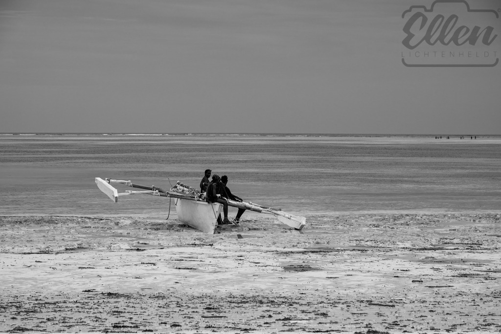 Low Tide Rest | At low tide on the coast of Zanzibar, fishermen rest beside their traditional dhow. Between sea and sky, silence and salt, this moment captures the rhythm of life shaped by the ocean’s breath. - Realisiert mit Pictrs.com