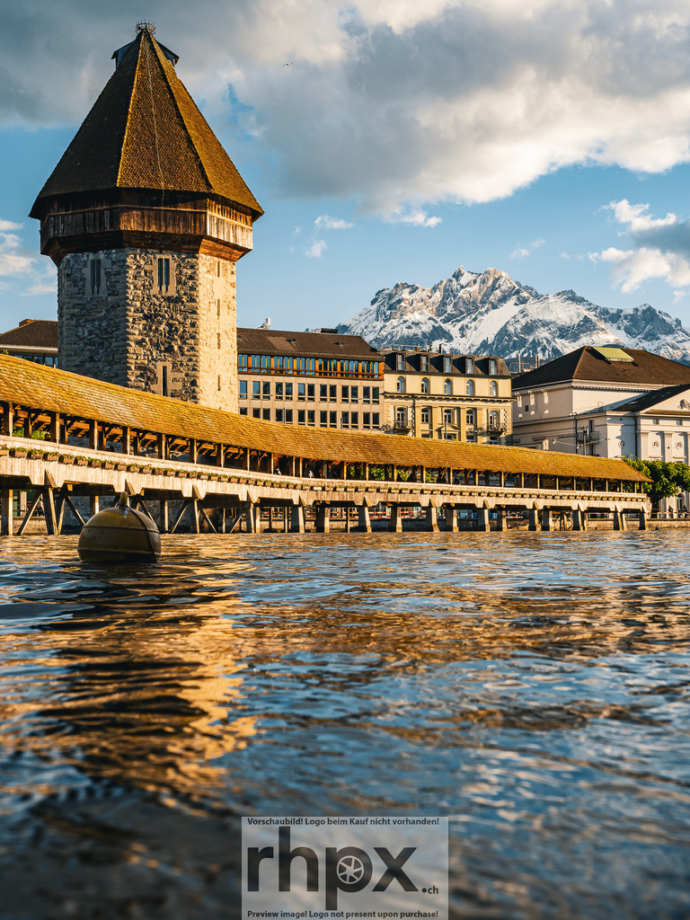 Kapellbrücke und Wasserturm Luzern im Abendlicht | Die tief stehende Sonne bricht sternförmig hinter dem Wasserturm hervor und taucht die Kapellbrücke sowie die Altstadt von Luzern in warmes Abendlicht.  - Realisiert mit Pictrs.com