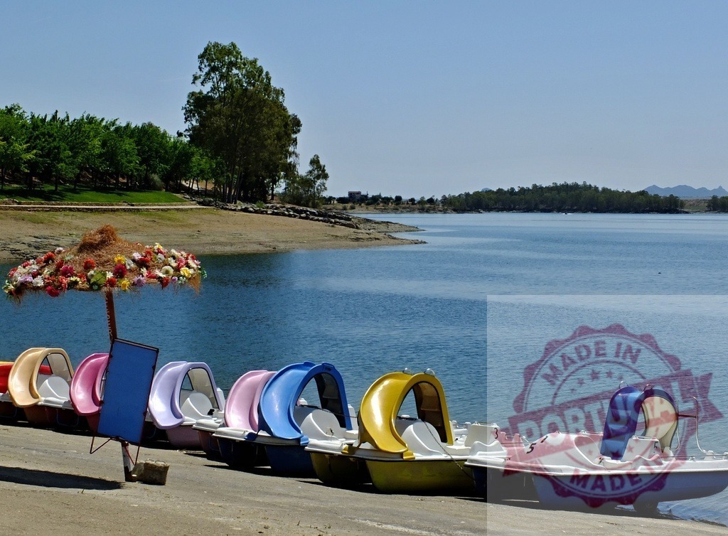 Colorful pedal boats lined up on lake shore. Spain - Extremadura | Pedal boats waiting for summer fun and water activities on a calm lake - Realisiert mit Pictrs.com