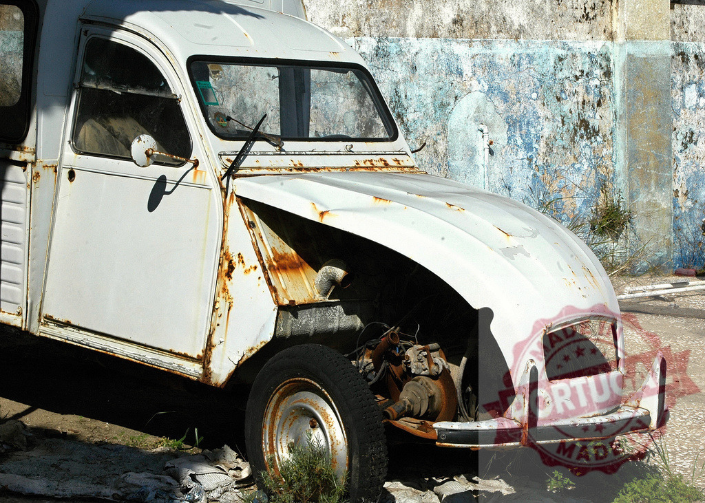 Rusty old Citroen 2CV abandoned against weathered wall | Vintage white Citroen 2CV showing significant rust damage stands abandoned near a deteriorating blue wall - Realisiert mit Pictrs.com