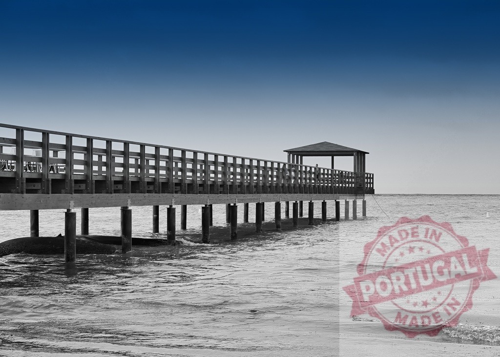 Wooden pier extending into ocean with small gazebo | Wooden pier stretching over the calm sea towards a small gazebo, under a blue sky - Realisiert mit Pictrs.com