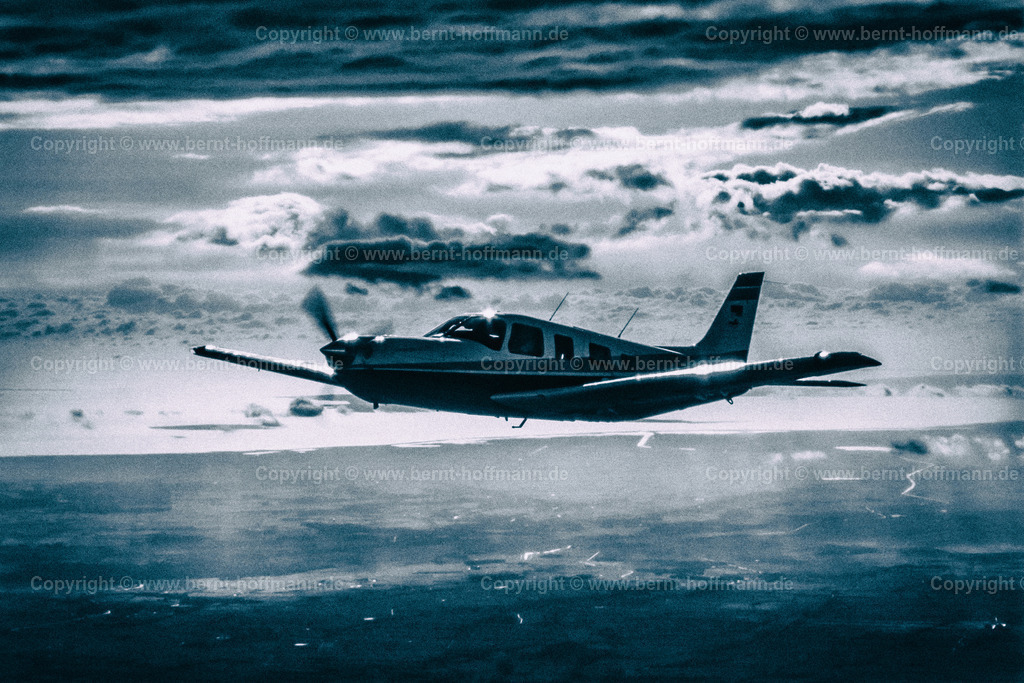 PLBDD_air2air_PiperSara_03e_90x60 | Luftbild. Einmotoriges Geschäftsflugzeug Typ " PIPER Saratoga II TC " im Licht der untergehenden Sonne vor der nordfriesischen Festlands- Küste. ____ Das Foto ist die Reproduktion von einem Farbdia. Bildanmutung schwarz-weiß Charakter mit Farbtonung Duoton blau. - Realisiert mit Pictrs.com