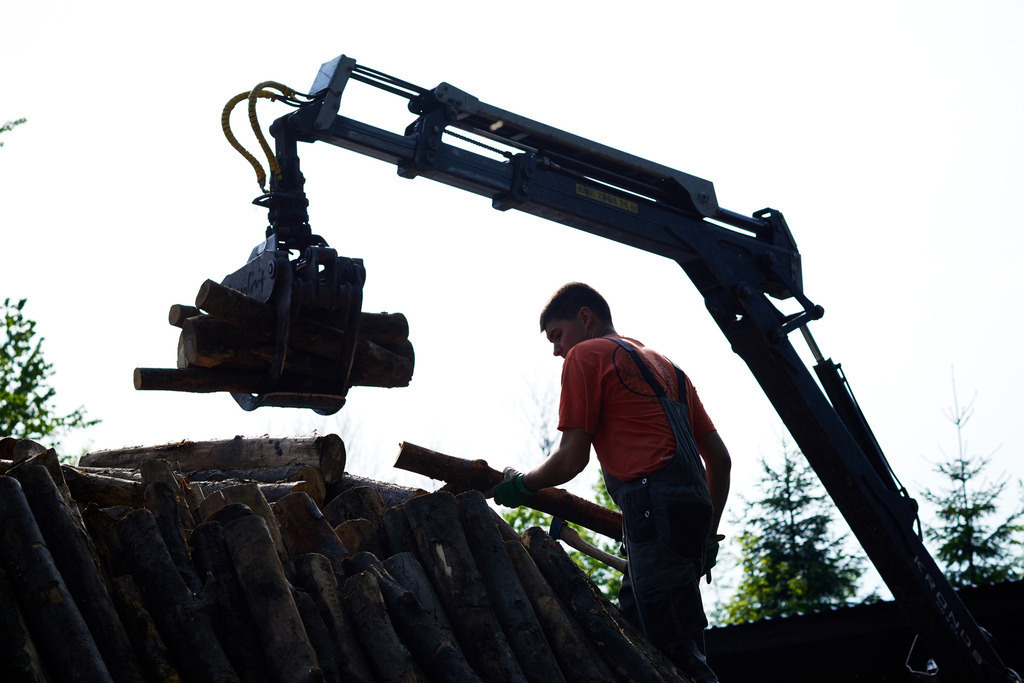 Arbeiten mit dem Holzkran am Kohlmeiler | Michelbach, Austria - May 08, 2019: Waldköhlerei Hochecker, die 2011 in das Nationale Verzeichnis des immateriellen Kulturerbes der UNESCO aufgenommen wurde, produziert noch echte Holzkohle, Arbeiten mit dem Holzkran am Kohlmeiler. - Realisiert mit Pictrs.com