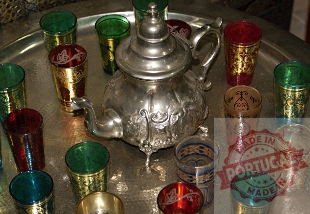 Moroccan tea service on a silver tray with colorful glasses | Traditional Moroccan mint tea setup with a silver teapot and decorative glasses on a metal tray - Realized with Pictrs.com
