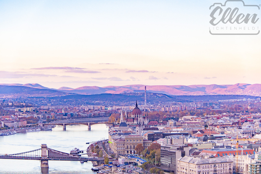 Lavender Light | Ein pastellfarbener Abend legt sich über Budapest, während sich die Donau sanft durch das Herz der Stadt schlängelt. Das Parlament leuchtet vor den violetten Hügeln – eine flüchtige Harmonie aus Architektur und Abendlicht. - Realisiert mit Pictrs.com