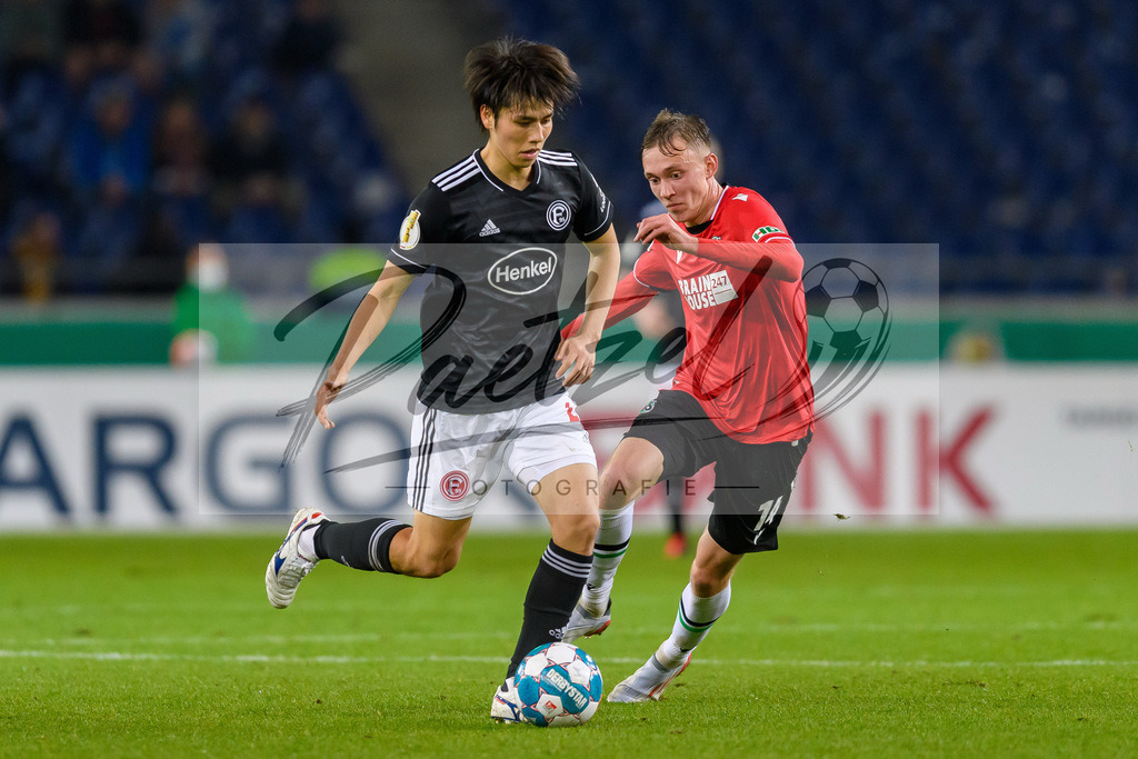 H96DUS20211027_031 | Fussball, Herren: Ao Tanaka (Fortuna Duesseldorf) und Maximilian Beier (Hannover 96) im Zweikampf bei dem Spiel der 2. Runde im DFB-Pokal zwischen Hannover 96 und Fortuna Duesseldorf in der HDI-Arena am 27.10.2021 in Hannover, Deutschland.DFB / DFL REGULATIONS PROHIBIT ANY USE OF PHOTOGRAPHS AS IMAGE SEQUENCES AND/OR QUASI-VIDEO. - Realisiert mit Pictrs.com