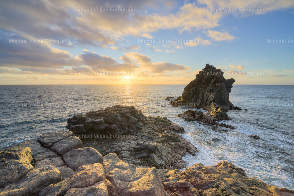 Ilhéu de Santa Cruz | Wenn der erste Lichtschimmer des Tages über den Atlantik tanzt, zeigt sich die Ilhéu de Santa Cruz in einer zauberhaften Kulisse. Dieses kleine, aber markante Felsinselchen vor der Küste von Santa Cruz auf Madeira wird beim Sonnenaufgang in warme Töne getaucht.Die sanften Strahlen der aufgehenden Sonne malen ein Gemälde aus leuchtendem Orange und goldenem Gelb über den Himmel und das ruhige Meer.An diesem friedlichen Ort bietet die aufgehende Sonne nicht nur ein visuelles Spektakel, sondern auch einen Moment der Stille und Einkehr. Das sanfte Rauschen der Wellen und die frische, salzige Meeresbrise erinnern daran, wie lebendig die Welt zu dieser frühen Stunde ist.Ein Sonnenaufgang bei der Ilhéu de Santa Cruz ist mehr als nur ein Anblick – es ist ein Erlebnis. Er lädt dazu ein, die Magie eines neuen Tages zu spüren und sich von der Natur inspirieren zu lassen. - Realisiert mit Pictrs.com