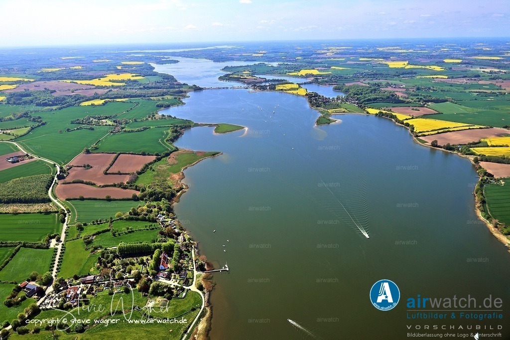Luftbild Ostseefjord Schlei in Schleswig-Holstein,  | Bereits im Mittelalter war die Schlei ein bedeutender Handelsweg im Ostseeraum, da der Landweg von Schleswig zur Treene, einem Nebenfluss der Eider, nur 16 Kilometer betrug, was eine günstige Stelle zum Warenaustausch zwischen Nord- und Ostsee bot. Die Wikinger nutzten diesen Weg, und die 1066 zerstörte Wikingersiedlung Haithabu vor Schleswig wurde bereits um 1075 von Adam von Bremen als Meereshafen (portus maritimus) beschrieben, von dem aus Schiffe bis Schweden und Griechenland segelten. Nach der Zerstörung von Haithabu übernahm Schleswig diese Rolle, verlor jedoch im 14. Jahrhundert an Bedeutung, als die Schiffe größer wurden und die Schlei zu flach wurde.