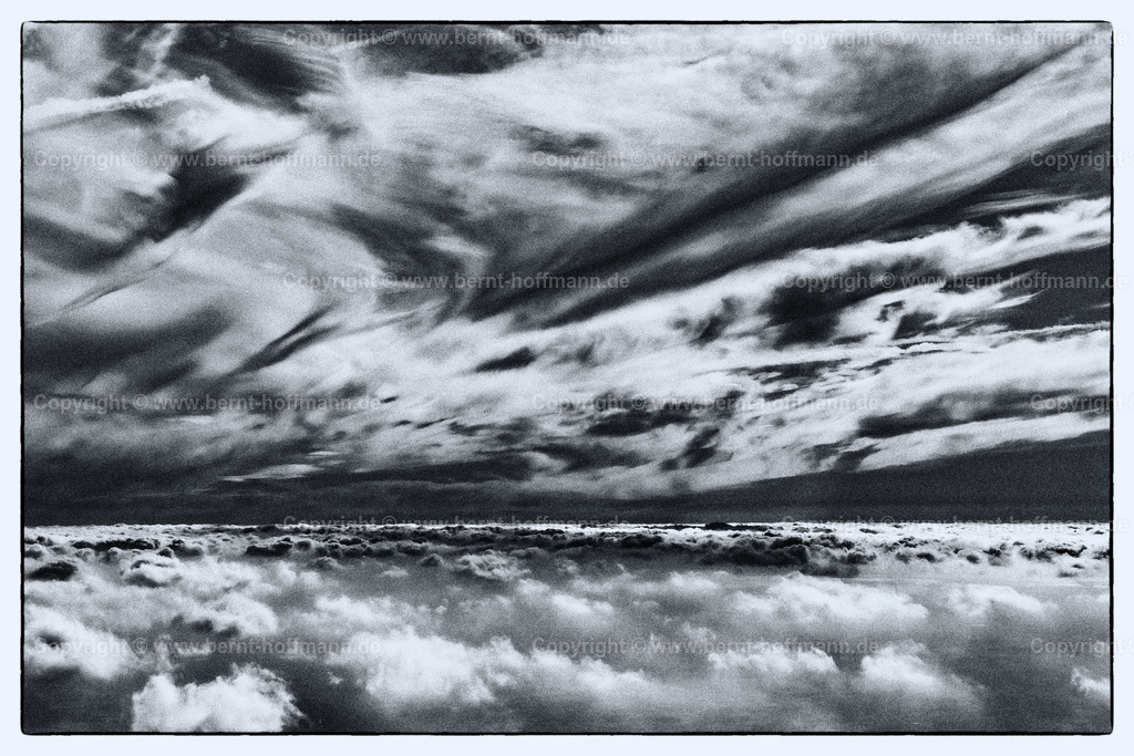 PLB_1453m_V3_Inversion_max90x60 | LUFTBILD. Flug über den Wolken – Inversionsschicht 03. __ Dunst und dünne Wolkendecke von oben betrachtet. Darüber ein wildes Himmelsbild mit Cirrus-Bewölkung. __ Anmutung = schwarzweiß -konvertiert. - Realisiert mit Pictrs.com