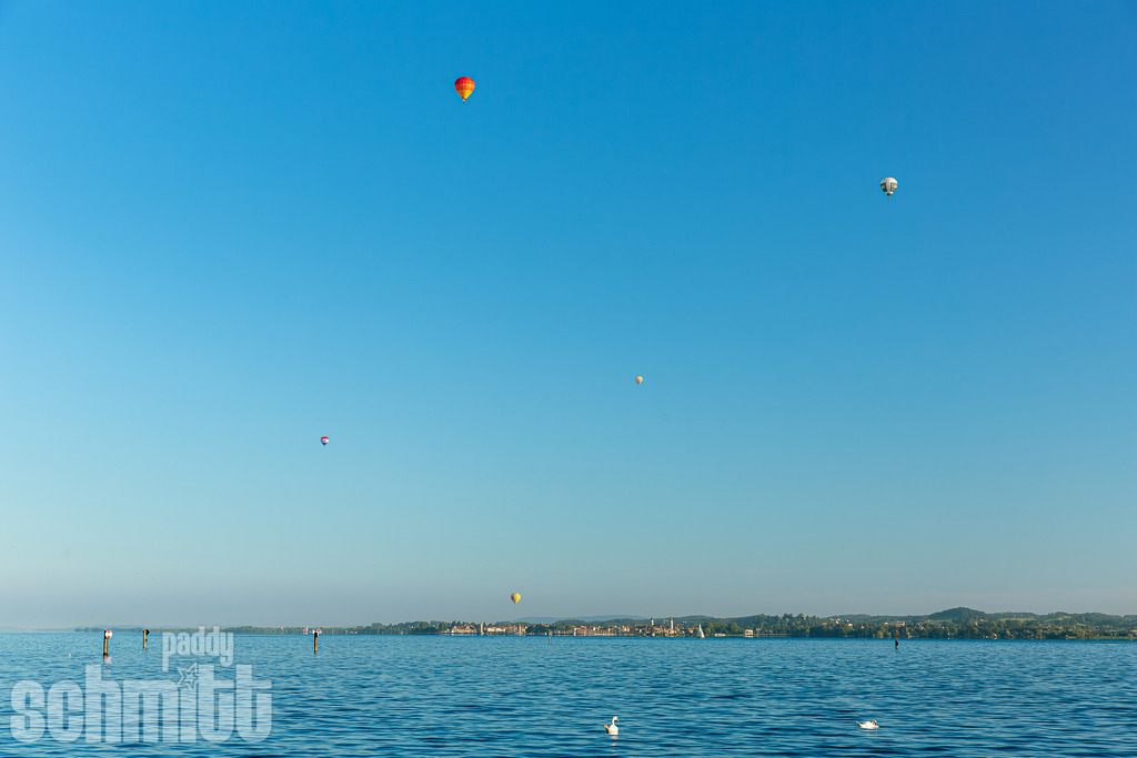 Ballone über der Insel Lindau am Bodensee | Bunte Heißluftballone schweben über der Insel Lindau und verleihen der Bodenseelandschaft eine ganz besondere Leichtigkeit. Vor der Kulisse von See und Wasser entsteht ein stimmungsvolles Motiv, das Freiheit, Weite und die Schönheit der Region verbindet. - Realisiert mit Pictrs.com