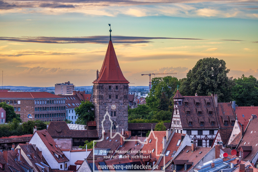Nürnberger Stadtbild am Abend | Das Tiergärtnertor und das Pilatushaus in Nürnberg, Bayern, Deutschland, während des Sonnenuntergangs. Historische Gebäude und Ziegeldächer der Altstadt sind im Vordergrund zu sehen. - Realisiert mit Pictrs.com