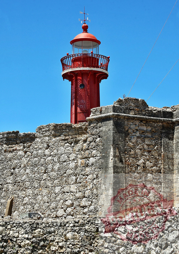Farol de Santa Marta lighthouse in Cascais, Portugal | Red Farol de Santa Marta lighthouse standing behind a stone fort wall in Cascais - Realisiert mit Pictrs.com