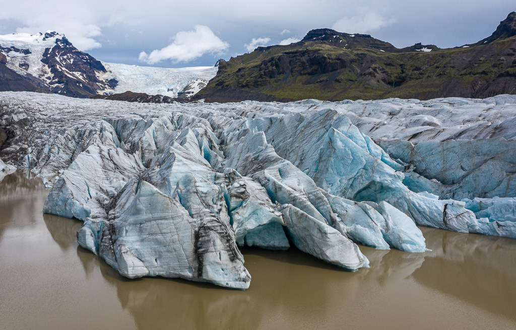 island-2020-408 | Die Gletscherzunge des Svínafellsjökull erstreckt sich weit in den gleichnamigen See, in dem Eisberge unterschiedlicher Größe treiben. - Realisiert mit Pictrs.com