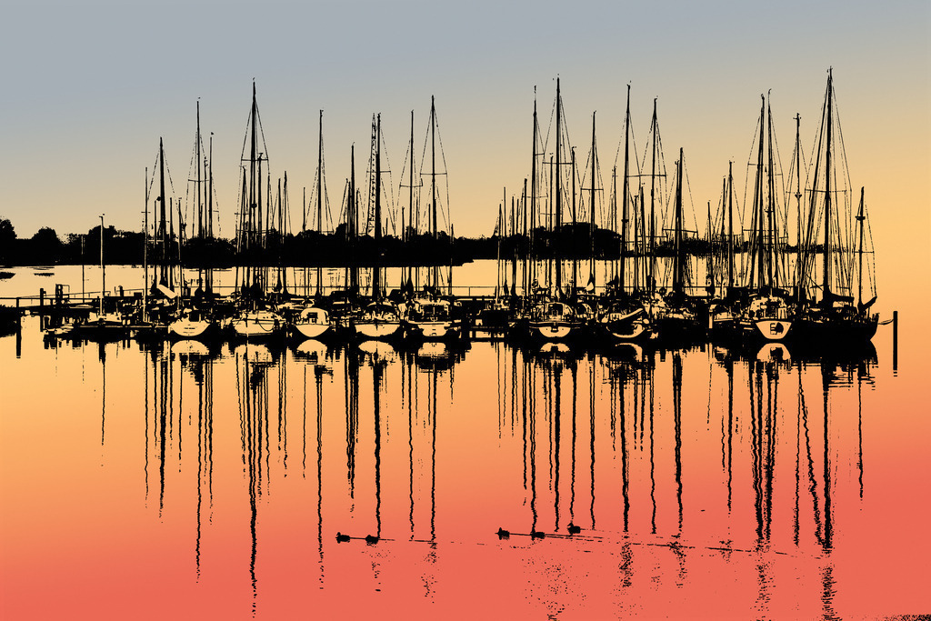 Photoart: Yachthafenspiegelung an der Schlei im Morgenrot | Dieses Wandbild im Querformat zeigt den Yachthafen in Lindaunis mit schöner Spiegelung auf der Schlei im Morgenrot. Die dunklen Bereiche sind dunkelblau und die zeigen eine schöne morgendliche Lichtstimmung aus warmen Farbtönen. Dem Wandbild wurde eine leichte Körnung hinzugefügt. Im Vordergrund schwimmen einige Enten auf der Schlei. Somit erhalten Sie ein exklusives Kunstwerk der Schleiregion. Zudem gibt es eine weitere Versionen dieses Motivs. - Realized with Pictrs.com