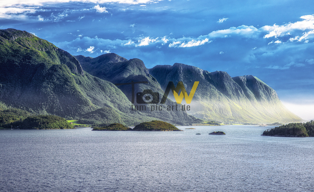 Bild einer malerischen Fjordlandschaft in Norwegen-Geiranger | Das Bild zeigt eine Landschaftsaufnahme von Bergen und einem Gewässer, die in Norwegen aufgenommen wurde. Die Aufnahme zeigt eine malerische Fjordlandschaft mit steilen, grünen Berghängen, die ins Wasser abfallen.Mehrere kleine Inseln sind im Gewässer sichtbar. - Realisiert mit Pictrs.com