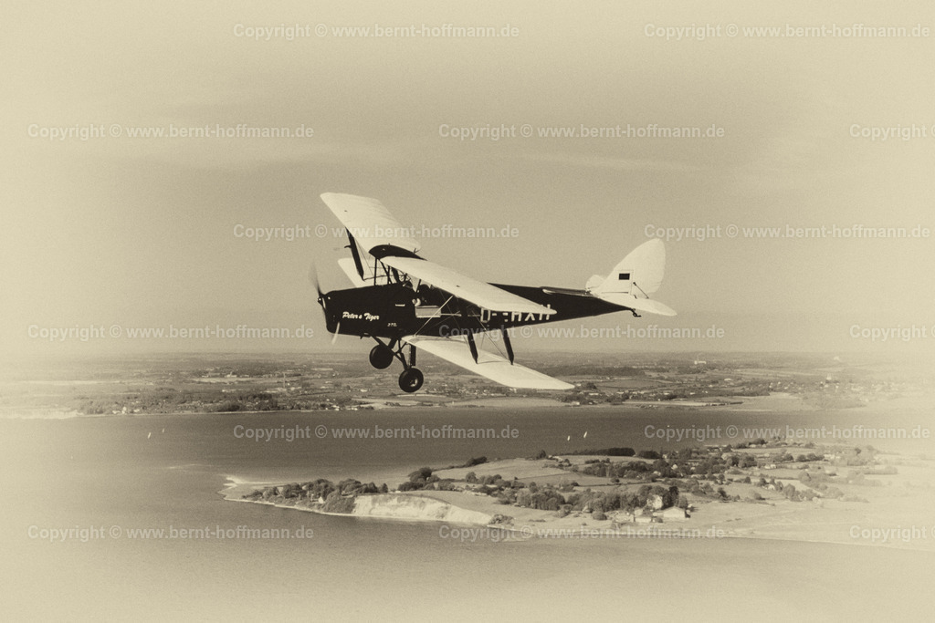 PLBDD_air2air_TigerMoth_02a_90x60 | Luftbild. Doppeldecker vom Typ TIGER MOTH vor dem Holnis Kliff über der Flensburger Innenförde. ___ Das Foto ist eine Reproduktion von einem Farbdia. Bildanmutung - schwarz-weiß Charakter mit Farbtonung. - Realisiert mit Pictrs.com