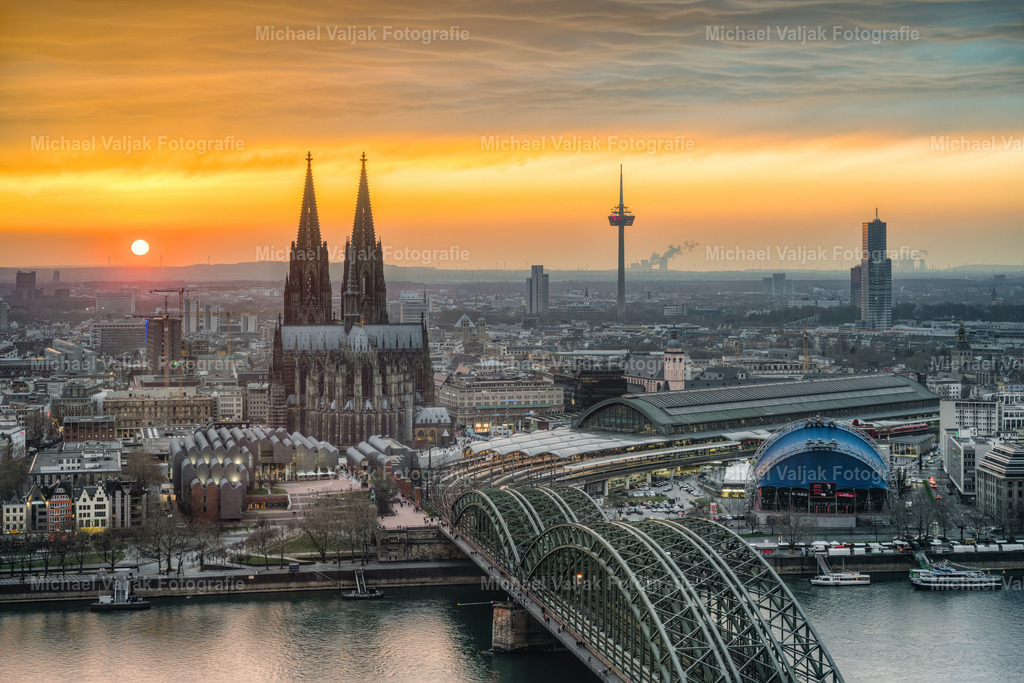 Blick über Köln bei Sonnenuntergang | Blick über Köln bei einem atemberaubenden Sonnenuntergang. Kurz bevor sie untergeht schafft sie es nochmal durch die Wolken und sorgt so für das intensive Farbspektakel am Himmel. Einer der schönsten Sonnenuntergänge in Köln die ich bisher erlebt und fotografiert habe. Bei dieser Version habe ich etwas näher herangezoomt. - Realisiert mit Pictrs.com