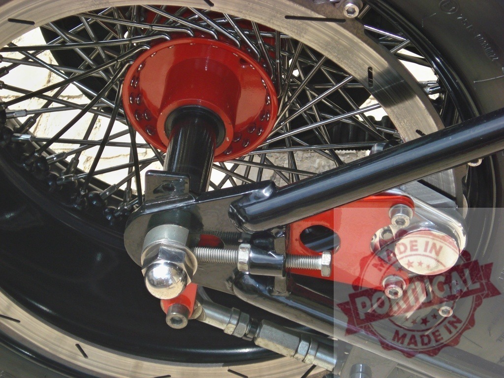 Red hub and spokes on custom motorcycle wheel | Custom motorcycle features a red hub, shiny spokes, and disc brake on a rear wheel - Realized with Pictrs.com