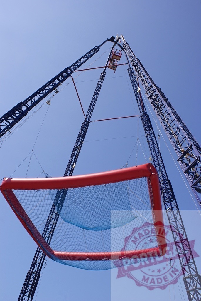 Bungee jumping safety net and amusement park structure | Amusement park bungee jump ride featuring a large safety net against a blue sky - Realisiert mit Pictrs.com